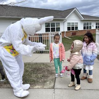 Children excitedly interact with an Easter Bunny character during a festive outdoor event.
