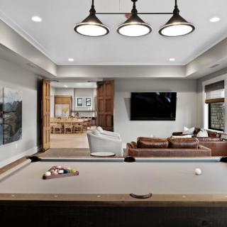 A modern living space featuring a pool table, seating area, and large television.