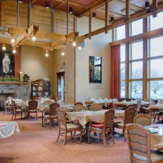 A cozy restaurant dining area featuring wooden ceilings, large windows, and neatly arranged tables and chairs.