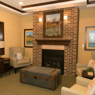 A cozy living room featuring a brick fireplace with seating and artwork.