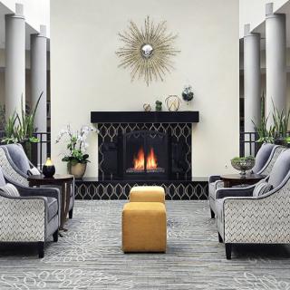 A modern living room with a cozy fireplace, stylish chairs, and decorative plants.