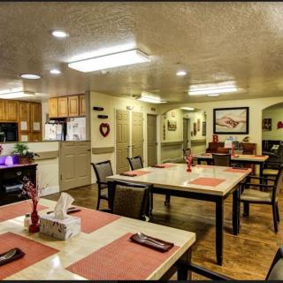 A cozy dining area with neatly arranged tables and chairs, adjacent to an open kitchen.