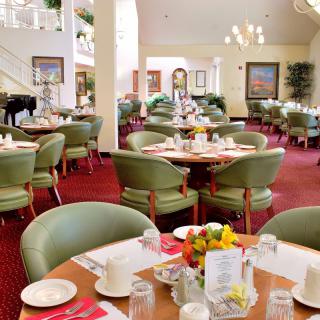 A well-lit restaurant interior with neatly arranged tables and chairs, floral centerpieces, and elegant decor.