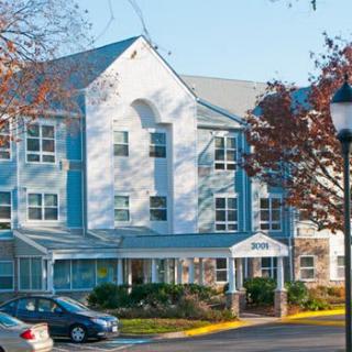 A residential building surrounded by trees and parked cars in an autumn setting.