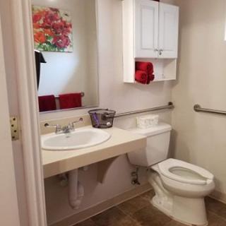 A well-organized bathroom with a sink, toilet, and red towels.