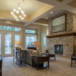 A cozy living room with a stone fireplace and elegant chandelier.