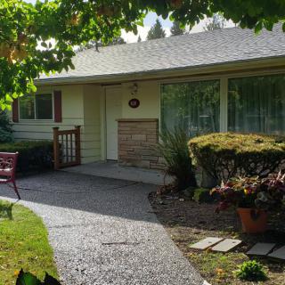 A quaint house with a well-maintained garden and pathway leading to the front door.