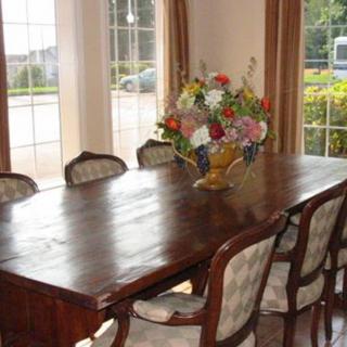 A dining room with a large wooden table and chairs, decorated with a bouquet of flowers by the window.