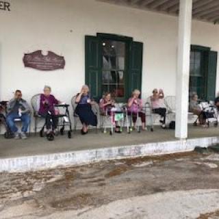 A group of seniors sitting on a porch, enjoying a peaceful moment together.