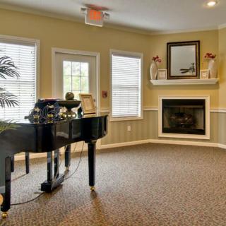 A cozy living room featuring a grand piano and fireplace.