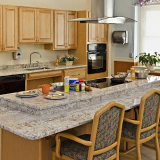 A spacious and modern kitchen featuring a granite countertop with bar stools and wooden cabinetry.