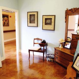 A cozy hallway featuring a wooden chair, dresser with mirror, and framed artwork on the walls.