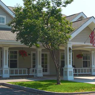 A charming suburban house with a spacious porch and an American flag.