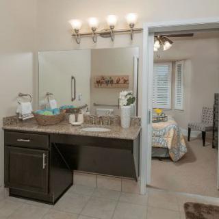 A spacious bathroom with a vanity area, connected to a cozy bedroom.