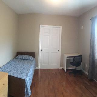 A minimalist bedroom with a single bed, desk, and chair.