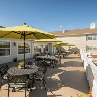 A spacious patio with tables, chairs, and umbrellas under a clear blue sky.