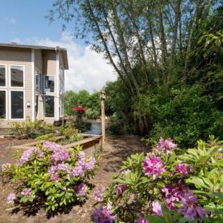 A beautiful garden with colorful flowers surrounds a modern house on a sunny day.