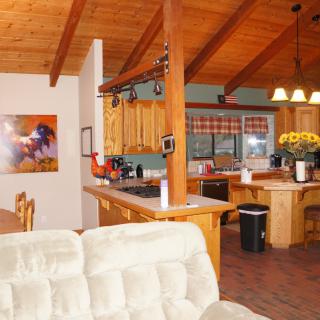A cozy open-plan kitchen and living area with a wooden ceiling and warm decor.