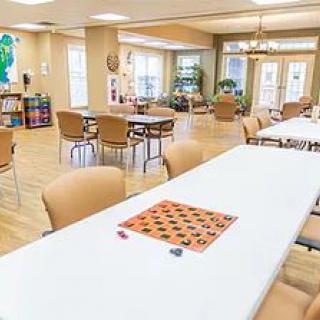 A spacious community room with tables and chairs, featuring a game board on the table.
