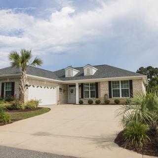 A single-story house with a two-car garage and palm trees in the driveway.