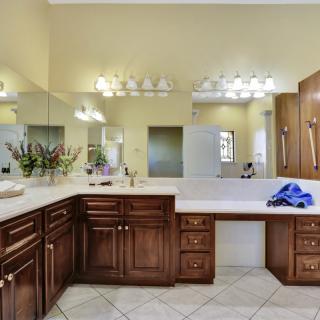 Spacious bathroom with a large mirror, wooden cabinets, and a bathtub.