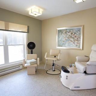 A modern spa salon room featuring a pedicure chair, contemporary artwork, and ample natural light.