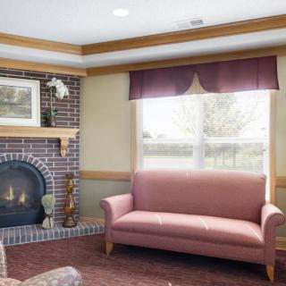 A cozy living room with a pink sofa, brick fireplace, and large window.