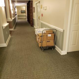 A quiet hallway with a cart carrying boxes, illuminated by soft lighting.