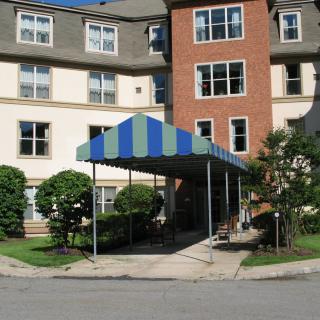 A residential building entrance with a blue and green striped awning.