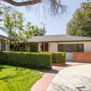 A charming residential house with a well-maintained front yard and a circular driveway under a sunny sky.
