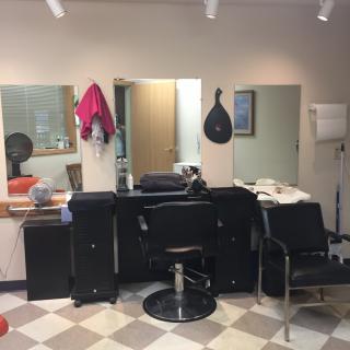 Interior view of a barber shop with chairs and mirrors.