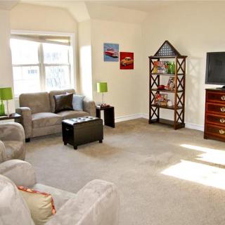 A bright living room with comfortable seating, a TV, and a decorative bookshelf.