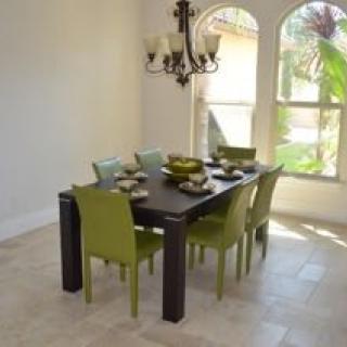 A modern dining room with green chairs and a dark wooden table.