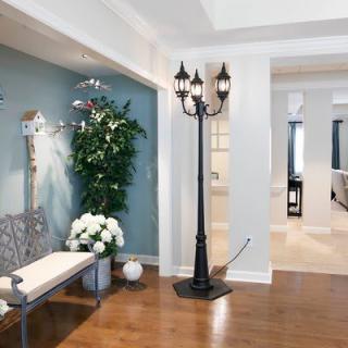 A modern hallway with stylish decor including a floor lamp, bench, and green plants.