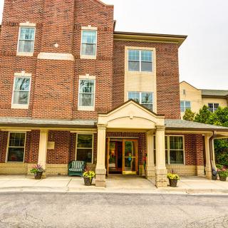 A three-story brick building with a covered entrance and multiple windows.