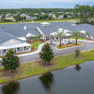 Aerial view of a large building complex surrounded by trees and situated near a lake.