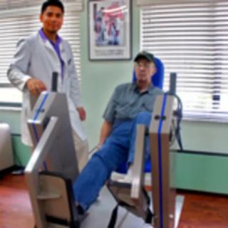 A medical professional assists a patient using exercise equipment for rehabilitation.