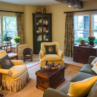 A cozy and traditionally styled living room with comfortable armchairs, a sofa, and a wooden coffee table.
