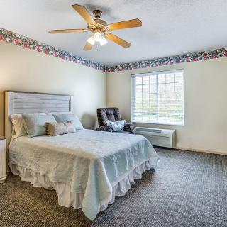 A cozy bedroom featuring a double bed, ceiling fan, and large window.