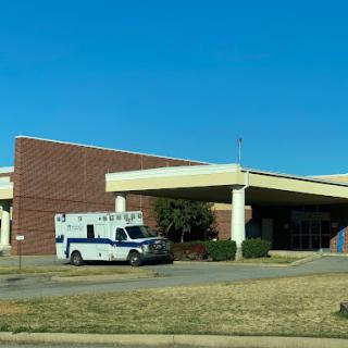An ambulance parked outside a healthcare facility under a clear blue sky.