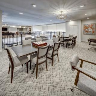 A modern interior living space with tables and chairs, featuring a well-lit environment and carpeted flooring.