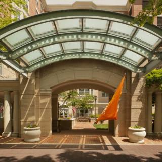 An elegant building entrance with a glass canopy and archway.