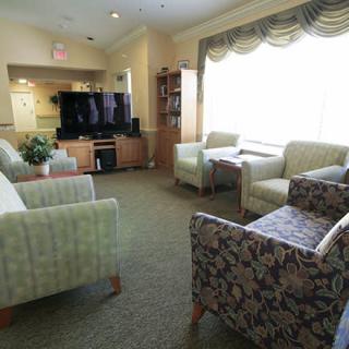 A cozy living room with comfortable seating and a large television, illuminated by natural light.