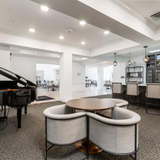 A stylish modern interior featuring a grand piano, bar area, and cozy seating arrangement.