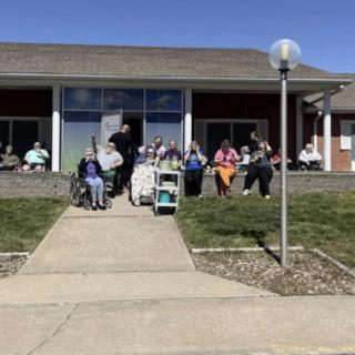 A group of people gathered outside a building on a sunny day.