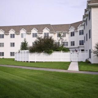 A residential apartment building with a well-maintained lawn and white fence.