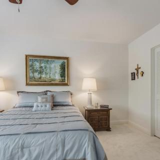 A cozy bedroom with a neatly made bed, flanked by two nightstands and lamps, adorned with a painting above the headboard.