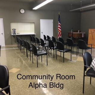 A community room set up for a meeting with chairs arranged and an American flag in the corner.