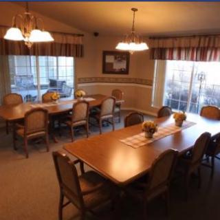 A spacious dining room with multiple tables and chairs, illuminated by ceiling lights.