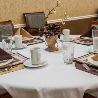 A elegantly set dining table with cups, glasses, and a decorative centerpiece.